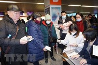 Cán bộ Đại sứ quán Việt Nam tại Ba Lan hỗ trợ thủ tục lên máy bay cho kiều bào sơ tán từ Ukraine. (Ảnh: Hồng Kỳ/TTXVN) 