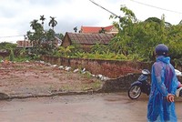 Một nhà đầu tư đội mưa để đi xem đất tại huyện Chương Mỹ. (Ảnh: Vũ Thanh)