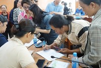 Người dân phấn khởi điền thông tin hộ gia đình để nhận quà Tết Độc lập. Ảnh: Hương Lý.