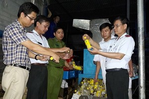 Đoàn thanh tra cùng đại diện Công ty URC Hà Nội giám sát việc tiêu hủy hàng không đạt chất lượng. (Ảnh: BYT cung cấp)