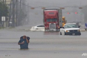 Một người đàn ông, vác theo đồ đạc trên lưng, lội qua đoạn ngập nước trên phố Telephone ở thành phố Houston, bang Texas, Mỹ vào ngày 27/8. Ảnh: AFP.