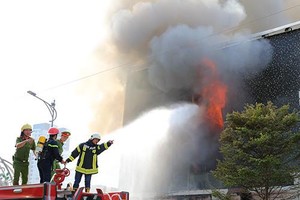 Lính cứu hoả tiếp cận dập lửa từ mặt tiền quán bar. Ảnh: Ngọc Trường.