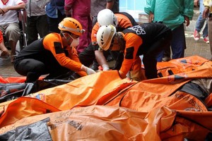 Lực lượng cứu hộ Indonesia bên cạnh túi đựng thi thể nạn nhân sáng 24/12. Ảnh: AFP.