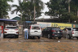 Tiệm rửa xe báo giá 200.000 đồng một lần rửa ôtô, song vẫn kín khách với nhiều người ngồi chờ trong sáng ngày 29 Tết. Ảnh: Minh Châu