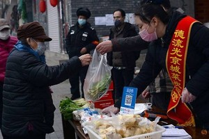 Nhân viên đứng bán tại sạp hàng dựng tạm trước cửa một trung tâm thương mại ở Bắc Kinh