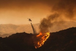 Máy bay trực thăng thả nước dập tắt các đám cháy tại Santa Clarita. Ảnh AFP.
