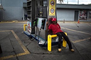Một nhân viên ngồi thất thần tại trạm xăng Petroleos de Venezuela tại Caracas, Venezuela. (Nguồn: Wil Riera | Bloomberg | Getty Images)