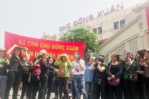 Nhiều tiểu thương căng băng rôn phản đối xây chợ sáng 9/4. Ảnh: Giang Huy.