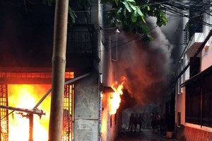 Căn nhà bốc cháy ngùn ngụt trong cơn mưa. Ảnh: Tin Tin.