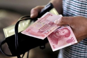 Người mua hàng cầm tờ 100 NDT tại một khu chợ ở Bắc Kinh. Ảnh: Reuters.