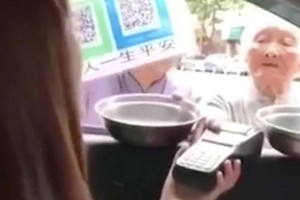 Một bà lão ăn xin người Trung Quốc đang xin tiền bằng máy POS quẹt thẻ ATM. (Nguồn: The Times).