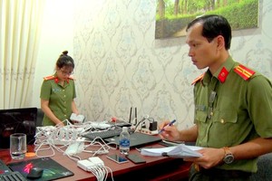 Công an kiểm đếm thiết bị điện tử tại nơi nhóm người Trung Quốc thuê để làm thẻ ATM giả và đánh bạc. Ảnh: Quang Bình.