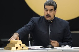 Tổng thống Maduro chạm vào các thỏi vàng trong cuộc họp với các bộ trưởng phụ trách lĩnh vực kinh tế ở Caracas tháng 3/2018. Ảnh: Reuters.