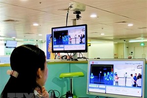 Nhân viên sân bay Tân Sơn Nhất kiểm tra màn hình hiển thị máy quét thân nhiệt đối với hành khách quốc tế đến Việt Nam. (Ảnh: Đinh Hằng/TTXVN).