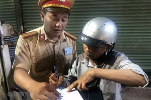 Lái xe môtô vi phạm nồng độ cồn ký biên bản vi phạm hành chính. (Ảnh: Nguyên Linh/TTXVN).