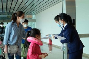 Nhân viên Sân bay quốc tế Cam Ranh phát tờ rơi hướng dẫn phòng dich COVID-19 cho hành khách tại khu vực nhập cảnh. (Ảnh: Nguyễn Dũng/TTXVN).