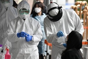 Nhân viên y tế Hàn Quốc lấy mẫu xét nghiệm nCoV cho một phụ nữ ở Seoul ngày 10/3. Ảnh: AFP.