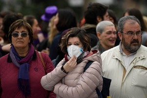 Một phụ nữ đeo khẩu trang giữa những người không có dụng cụ bảo hộ nào tại sự kiện kỷ niệm Ngày Quốc tế Phụ nữ 8/3 ở Madrid, Tây Ban Nha. Ảnh: AFP.