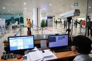Lực lượng y tế kiểm tra thân nhiệt đối với hành khách nhập cảnh. (Ảnh: Doãn Tấn/TTXVN).