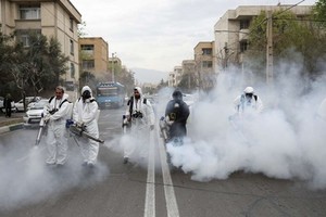 Nhân viên cứu hỏa trong trang phục bảo hộ khử trùng đường phố ở thủ đô Tehran, Iran, ngày 18/3. Ảnh: Reuters.