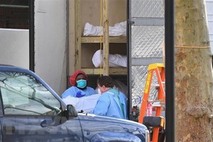 Nhân viên y tế chuyển thi thể bệnh nhân COVID-19 từ một nhà xác dã chiến tới Trung tâm y tế Do thái Kingsbrook ở Brooklyn, New York, Mỹ. (Ảnh: AFP/TTXVN).