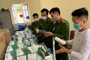 Lực lượng công an kiểm tra lô hàng khẩu trang vừa bị thu giữ. (Nguồn: TTXVN phát).