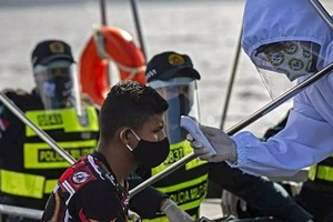 Nhân viên y tế chính phủ Brazil phối hợp cùng cảnh sát kiểm tra thân nhiệt cho một khách đi tàu ở bang Para hôm 27/5. Ảnh: AFP.