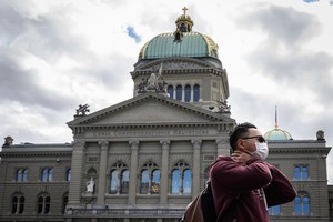 Du khách đeo khẩu trang đi ngang qua Tòa nhà Quốc hội Thụy Sĩ. (Nguồn: AFP).