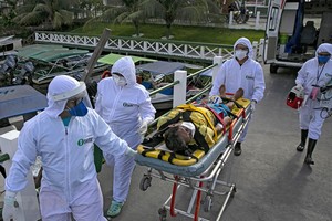 Nhân viên y tế chuyển bệnh nhân mắc COVID-19 tới một bệnh viện ở bang Para, Brazil. (Ảnh: AFP/TTXVN).