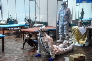 Nhân viên y tế và một bệnh nhân Covid-19 nhỏ tuổi thực hiện động tác yoga tại một bệnh viện Ấn Độ. Ảnh: AFP.