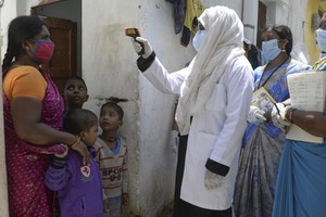 Nhân viên y tế kiểm tra thân nhiệt người dân ở thành phố Hyderabad, Ấn Độ, hôm 24/9. Ảnh: AFP.