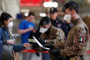 Cảnh sát và quân đội kiểm tra hành khách tại một nhà ga ở Milan, Italy. Ảnh: AP.