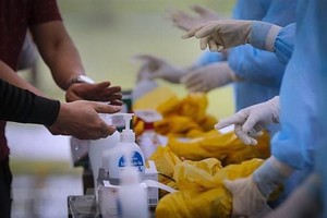 Các công dân thực hiện rửa tay bằng dung dịch khử trùng ngay khi về đến khu cách ly, trước khi được các bác sỹ phát đồ dùng cá nhân. (Ảnh: Trọng Đạt/TTXVN).