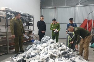 Lực lượng chức năng tiến hành kiểm tra số hàng nhái các thương hiệu nổi tiếng tại cửa hàng nhà ông H. (Ảnh: P.T).