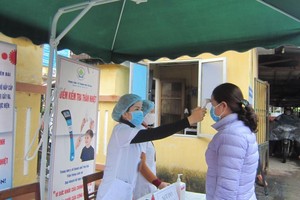 Cán bộ Trung tâm Y tế thành phố Yên Bái kiểm tra thân nhiệt cho bệnh nhân đến khám tại đơn vị (Ảnh: KT).