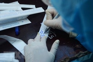 Nhân viên y tế ghi thông tin người dân vào mẫu xét nghiệm. (Ảnh: Văn Dũng/TTXVN).