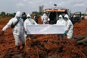 Nhân viên mặc đồ bảo hộ chôn cất nạn nhân Covid-19 tại Jakarta (Ảnh: Reuters).