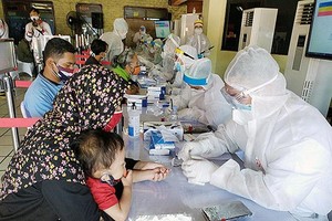 Một người mẹ cho con nhỏ xét nghiệm Covid-19 ở Jakarta, Indonesia (Ảnh: Jakarta Post).