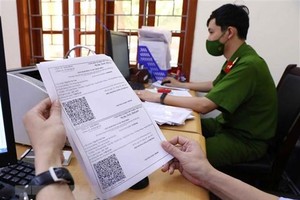 Giấy đi đường có mã nhận diện được lực lượng công an phường Văn Quán, quận Hà Đông đối chiếu và xét duyệt để cấp cho các cá nhân và doanh nghiệp thực hiện dịch vụ công ích thiết yếu trên địa bàn. (Ảnh: Phạm Kiên/TTXVN).