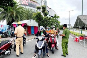 Lực lượng Công an tại chốt kiểm trên đường Phạm Văn Đồng, phường Hiệp Bình Chánh, Thủ Đức, kiểm tra giấy tờ của người lưu thông. (Ảnh: Thành Chung/TTXVN).