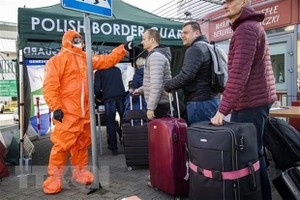 Nhân viên y tế kiểm tra thân nhiệt hành khách đi qua cửa khẩu biên giới Đức-Ba Lan. (Nguồn: AFP/TTXVN).