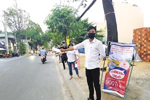 Nhân viên môi giới phát tờ rơi để tìm khách hàng. Ảnh: Lê Toàn.