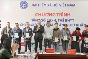 Phó Chủ tịch chuyên trách HĐQL BHXH Nguyễn Văn Cường trao tặng sổ BHXH, thẻ BHYT tới người dân.