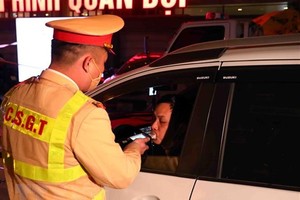 Cán bộ, chiến sỹ thuộc tổ công tác Y6/141 kiểm tra nồng độ cồn 1 tài xế ô tô tại đường Xã Đàn-Nam Đồng. (Ảnh: Phạm Kiên/TTXVN)