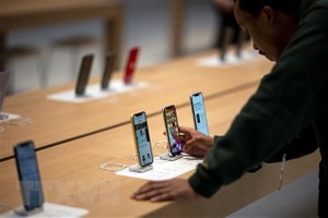 Khách hàng trải nghiệm điện thoại iPhone tại cửa hàng của Apple ở New York, Mỹ. (Ảnh: AFP/TTXVN)