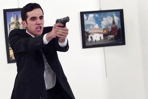 Mevlut Mert Altintas chĩa súng tại phòng triển lãm ảnh. Ảnh: AP