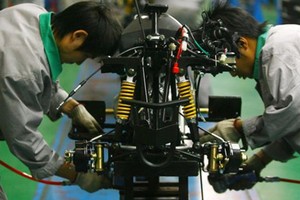 Công nhân Trung Quốc lắp ráp xe máy. Ảnh:AFP.