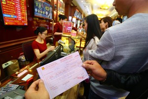 Khách hàng cầm trên tay giấy hẹn lấy vàng ngày vía Thần Tài tại một cửa hiệu vàng trên phố Trần Nhân Tông