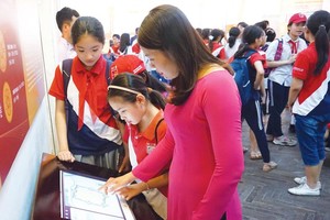 Du khách trải nghiệm màn hình diễn giải lịch sử tại Khu trung tâm Hoàng thành Thăng Long - Hà Nội.