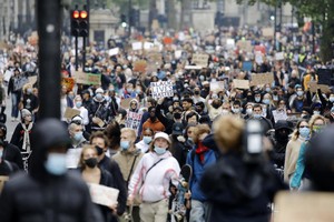 Các nhà hoạt động cầm biểu ngữ, đeo khẩu trang phòng dịch Covid-19 khi tham gia cuộc tuần hành theo phong trào hoạt động quốc tế "Black Lives Matter" (Người da đen đáng được sống) đến Quảng trường Trafalgar, London vào ngày 12/6/2020. Ảnh tư liệu: AFP